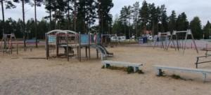 Alakoulun leikkipihan keinuja ja kiipeilytelineitä. Piha on pinnoitettu hiekalla.